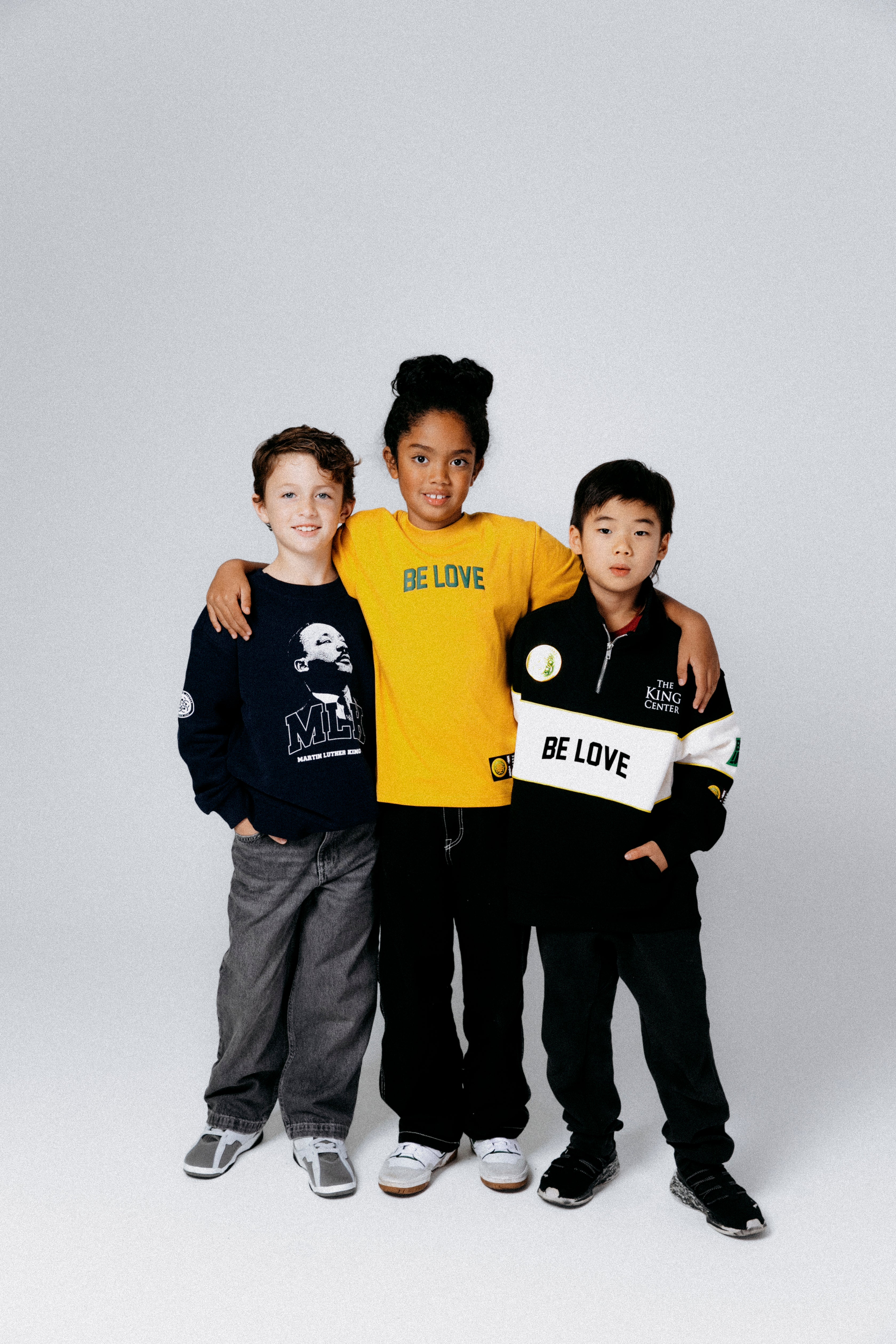 Three children wearing 'BE LOVE' branded clothing on a white background